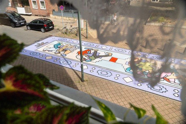 Kunstwerk am Platz an der Düsseldorfer Straße von Konstantin Zayka Blick aus einem Wohnzimmerfenster auf die bunt bemalte Straße.